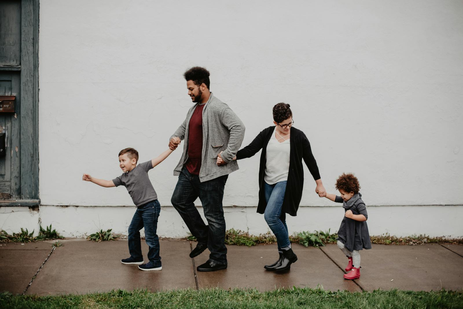 A joyful family walking together outdoors, holding hands in a playful and happy moment.